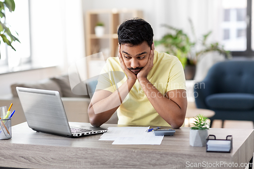 Image of man with calculator and papers working at home