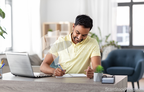 Image of indian man with notebook and laptop at home office