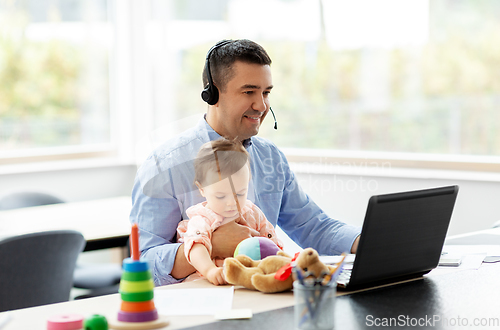 Image of father with baby working on laptop at home office