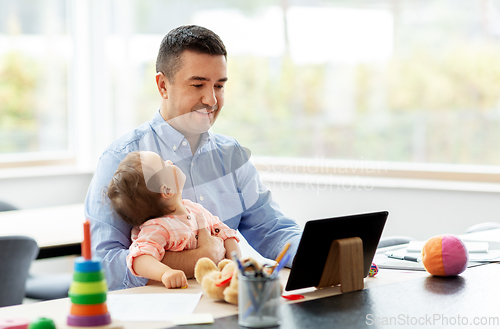 Image of father with baby working on tablet pc at home