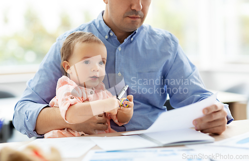 Image of father with baby working at home office