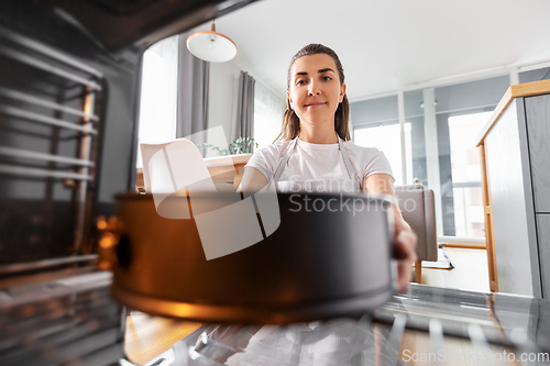 Image of woman cooking food in oven at home kitchen