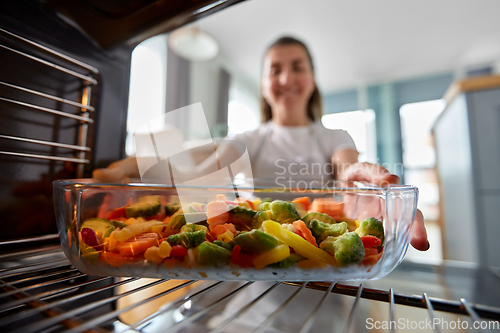 Image of woman cooking food in oven at home kitchen