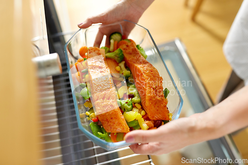 Image of woman cooking food in oven at home kitchen