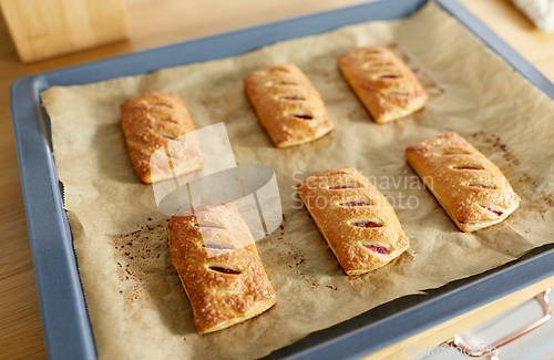 Image of baking tray with jam pies at home kitchen