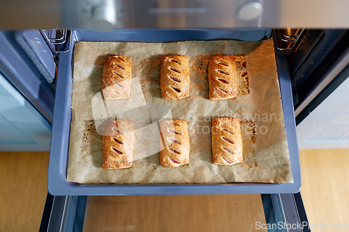 Image of baking tray with jam pies in oven at home kitchen