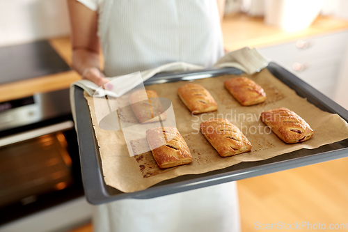 Image of woman holding baking tray with pies at kitchen