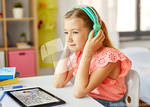 Image of girl in headphones with tablet computer at home
