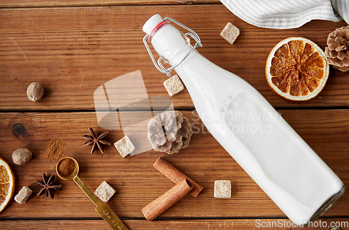 Image of bottle of milk and spices and sugar on wood