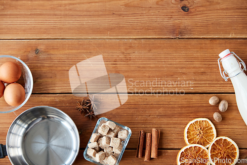 Image of ingredients for eggnog, sugar and spices on wood