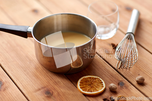 Image of pot with eggnog, whisk and spices on wood