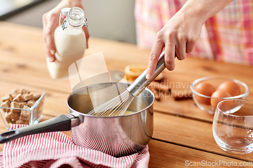 Image of hands with whisk and milk cooking eggnog