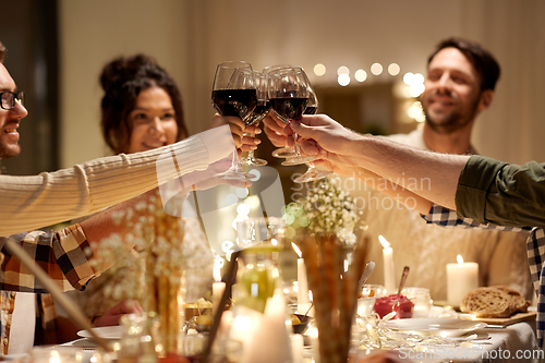 Image of happy friends drinking red wine at christmas party