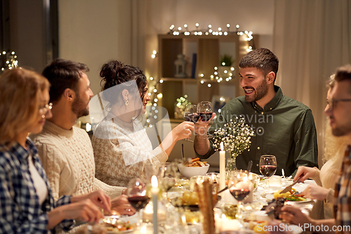 Image of happy friends drinking red wine at christmas party