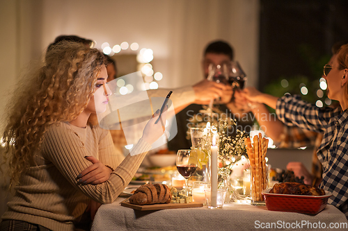 Image of woman with smartphone at dinner party with friends