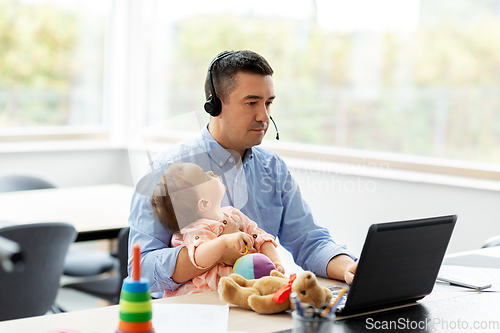 Image of father with baby working on laptop at home office