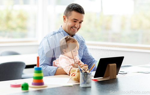 Image of father with baby working on tablet pc at home