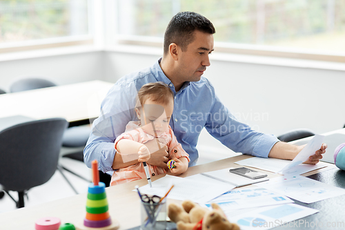 Image of father with baby working at home office