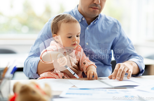 Image of father with baby working at home office