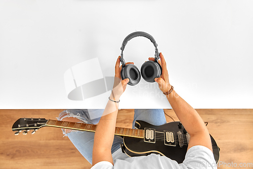 Image of young man with headphones and guitar at table