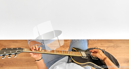 Image of young man playing guitar sitting at table