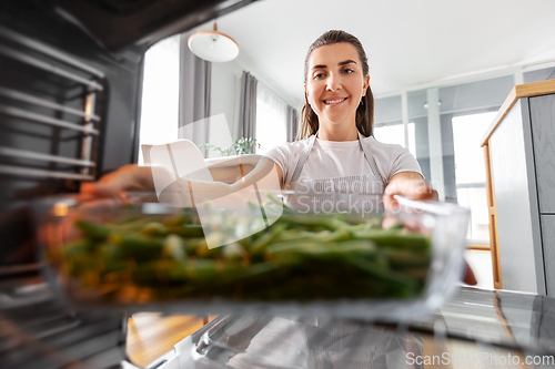 Image of woman cooking food in oven at home kitchen