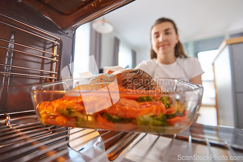 Image of woman cooking food in oven at home kitchen