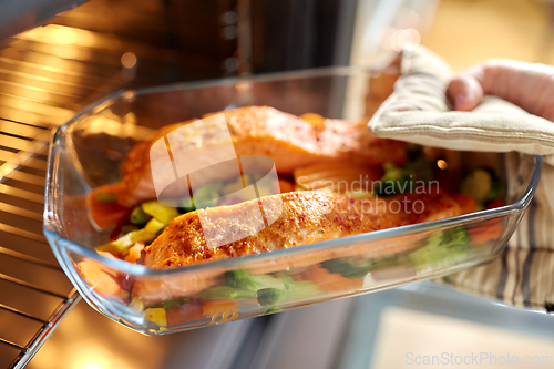 Image of woman cooking food in oven at home kitchen