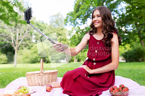 Image of happy woman with smartphone taking selfie at park