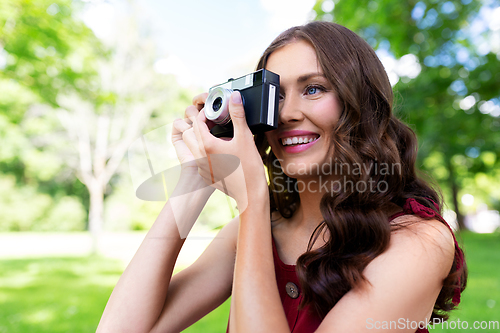 Image of happy woman with camera photographing at park