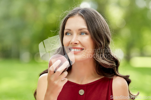 Image of happy woman eating peach at summer park