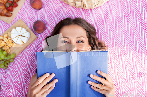 Image of happy woman reading book at picnic in summer park