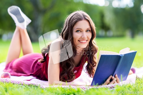 Image of happy smiling woman reading book at summer park