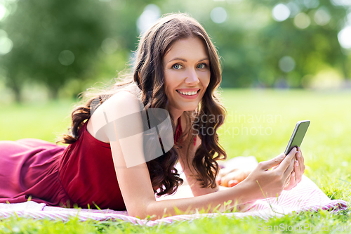 Image of happy woman with smartphone at park