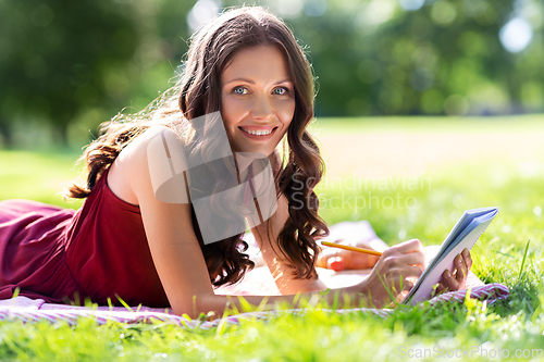 Image of happy woman with diary or notebook at park