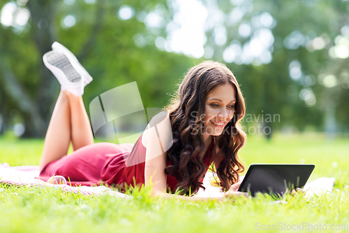 Image of happy woman with tablet computer on picnic at park