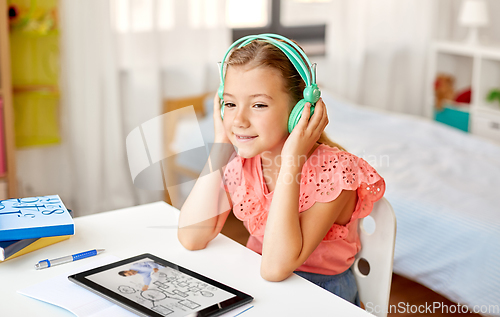 Image of girl in headphones with tablet computer at home