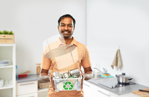 Image of smiling young indian man sorting metallic waste