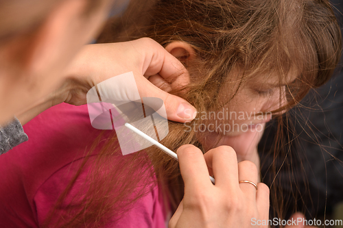 Image of Mom tries to comb the girl's badly tangled hair