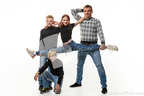 Image of Dad and son hold their daughter on a stretch, the second son sits next to him, full-length portrait, white background