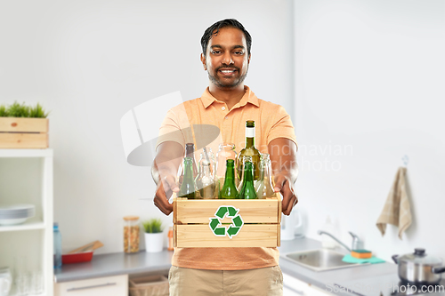 Image of smiling young indian man sorting glass waste