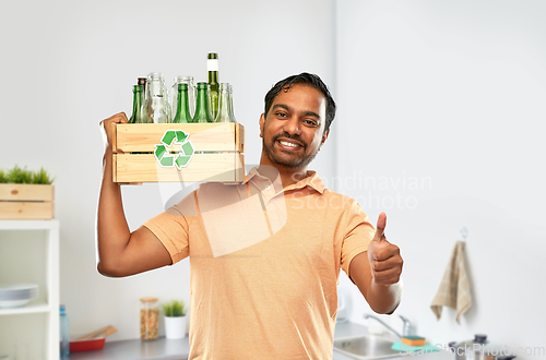 Image of smiling young indian man sorting glass waste