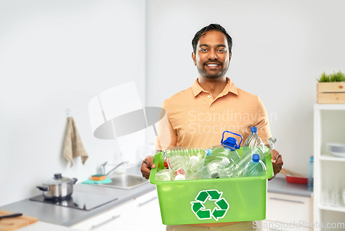 Image of smiling young indian man sorting plastic waste