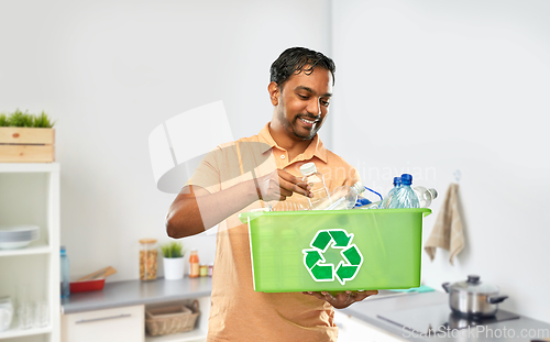 Image of smiling young indian man sorting plastic waste