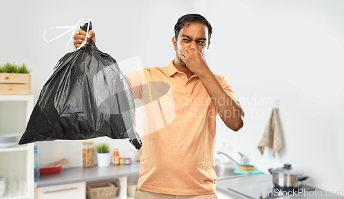 Image of indian man holding stinky trash bag