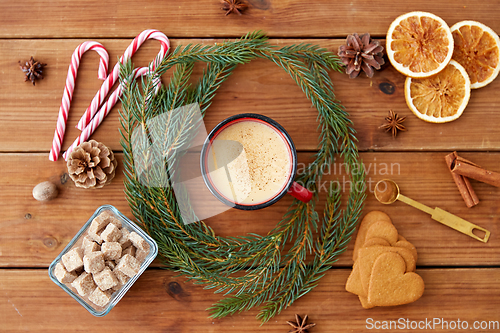 Image of cup of eggnog, fir branches, gingerbread and sugar