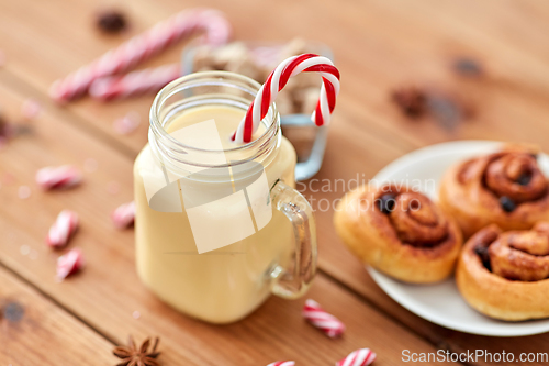 Image of eggnog with candy cane in mug and cinnamon buns