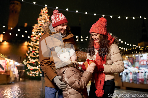 Image of happy family with gift at christmas market in city