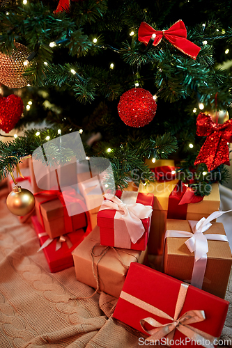 Image of gift boxes under decorated christmas tree at home