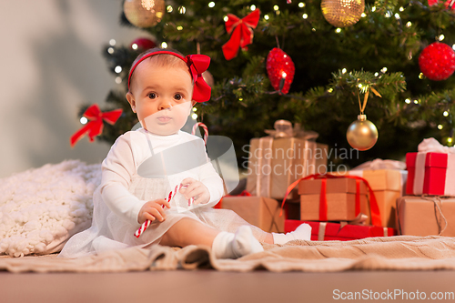 Image of baby girl at christmas tree with gifts at home